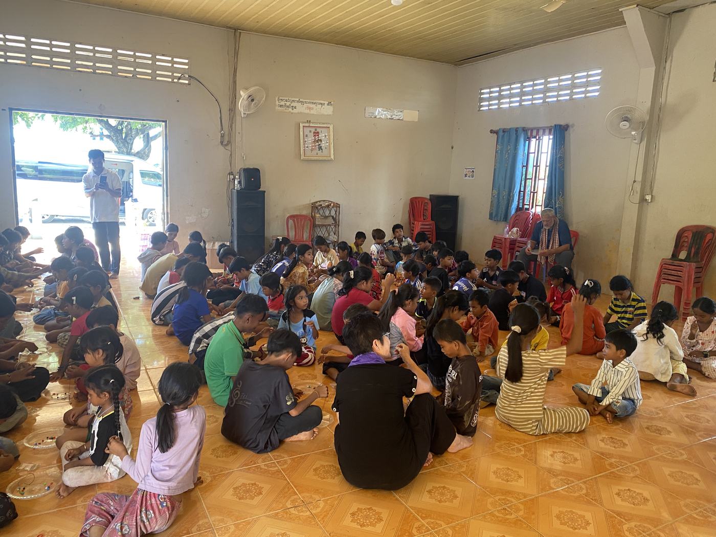 A room full of children gathered on the floor for a meeting in Cambodia